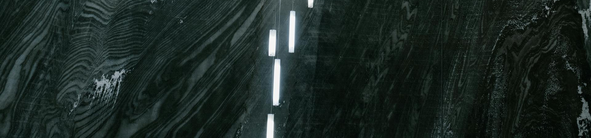 Interior of a mine with mining lights dangling against a black, dark, background.